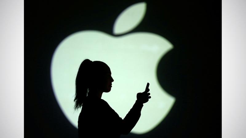 Silhouette of mobile user is seen next to a screen projection of Apple logo in this picture illustration taken on March 28, 2018. REUTERS