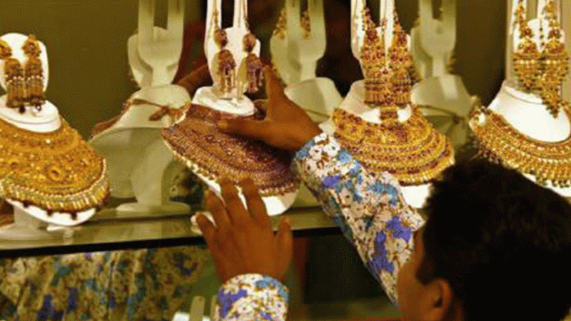A salesman arranges gold necklaces at a jewellery shop. REUTERS