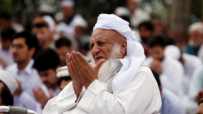 A man holds his palms together along with others during Eid al-Fitr prayers at a park in Peshawar, Pakistan.