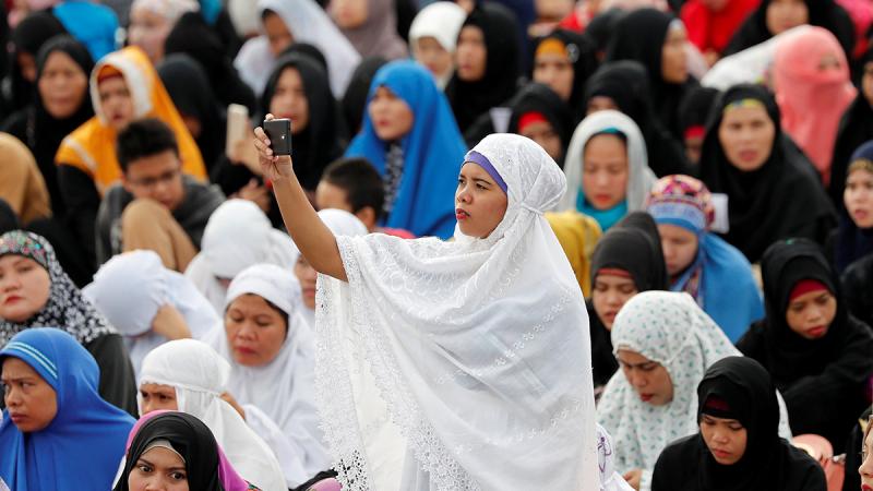 A Filipino Muslim woman takes a selfie during the first day celebration of Eid al Fitr at Luneta Park in Manila, Philippines June 15, 2018. REUTERS