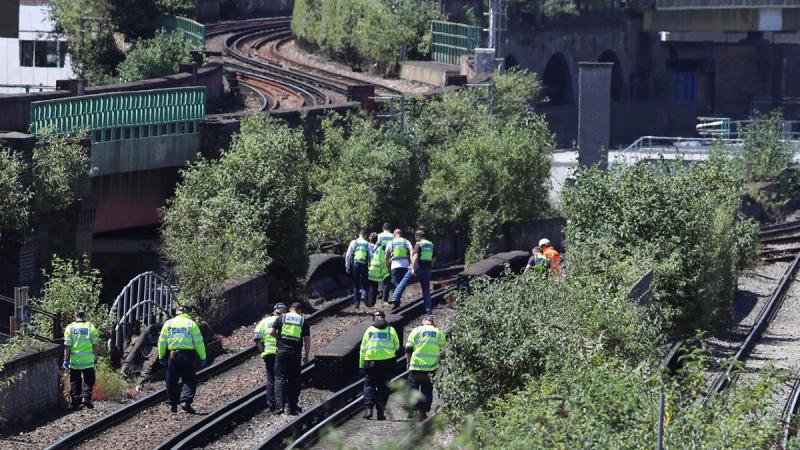 Police officers search near to where three people were found dead on a section railway track in south London, Britain, June 18, 2018. REUTERS