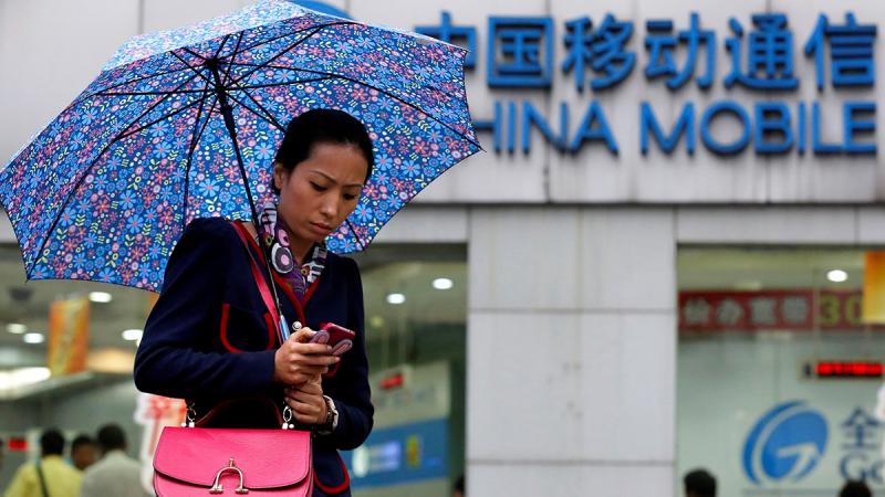 A woman uses her mobile phone in front of a China Mobile office in downtown Shanghai Oct 22, 2012. REUTERS