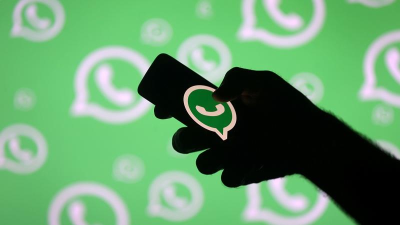 A man poses with a smartphone in front of displayed Whatsapp logo in this illustration Sep 14, 2017. REUTERS
