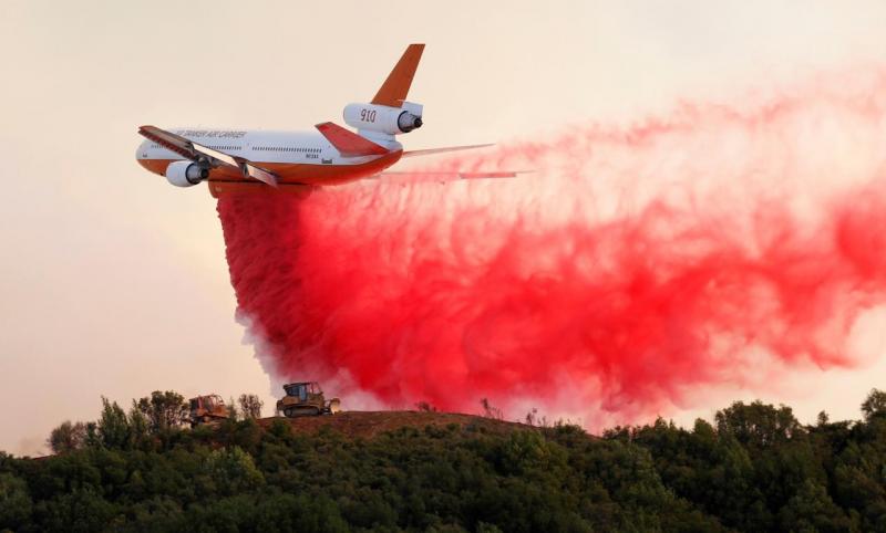 A DC-10 air tanker drops fire retardant along the crest of a hill to protect the two bulldozers below that were cutting fire lines at the River Fire (Mendocino Complex) near Lakeport, California, U.S. August 2, 2018. REUTERS