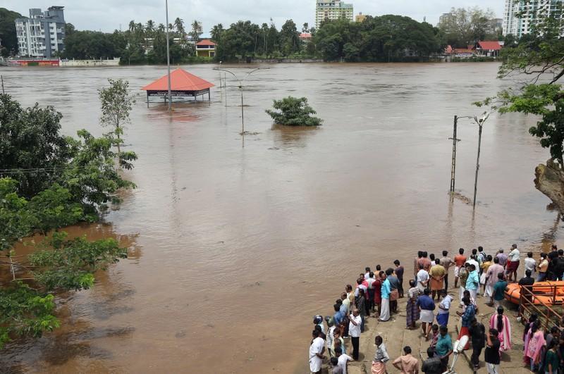 People stand on the steps of Aluva Shiva Temple complex submerged in water after the opening of Idamalayar dam shutter following heavy rains, on the outskirts of Kochi, India, August 9, 2018. REUTERS/FILE PHOTO