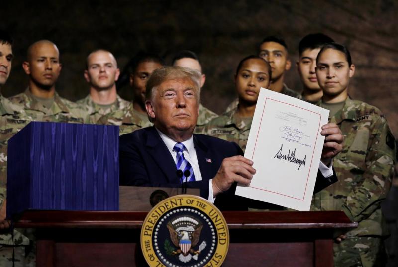 U.S. President Donald Trump holds up the National Defense Authorization Act after signing it in front of soldiers from the U.S. Army`s 10th Mountain Division at Fort Drum, New York, U.S., August 13, 2018. REUTERS