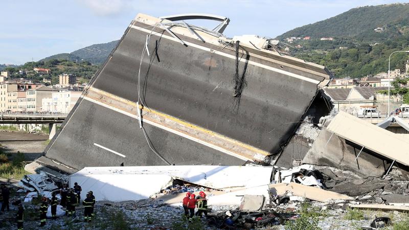 Firefighters and rescue workers stand next to a part of the motorway, at the collapsed Morandi Bridge site in the port city of Genoa, Italy Aug 14, 2018. REUTERS