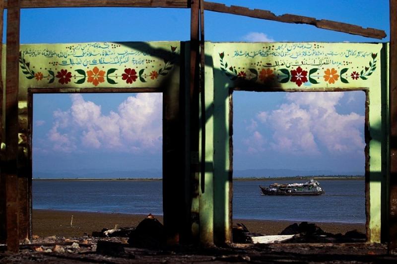 A boat is framed by the ruins of a destroyed mosque in a part of Pauktaw township that was burned in recent violence October 27, 2012. REUTERS/FILE PHOTO