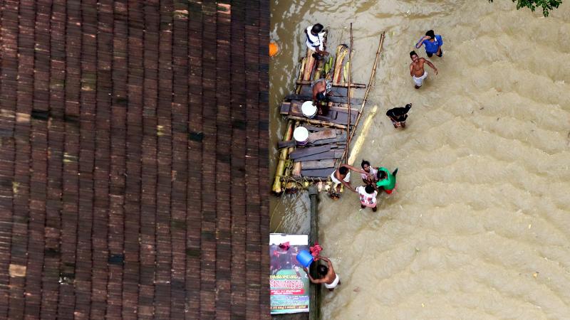 eople wait for aid next to makeshift raft at a flooded area in the southern state of Kerala, India, August 19, 2018. REUTERS