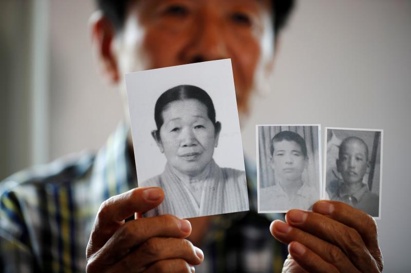 A man selected as a participant for a reunion shows pictures of his deceased mother and little brothers living in North Korea, Aug 19. REUTERS