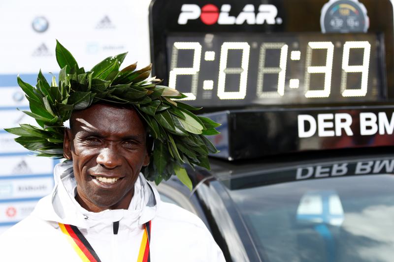 Kenya`s Eliud Kipchoge celebrates after winning the Berlin Marathon alongside a clock showing his World Record breaking time, Berlin, Germany September 16, 2018. REUTERS