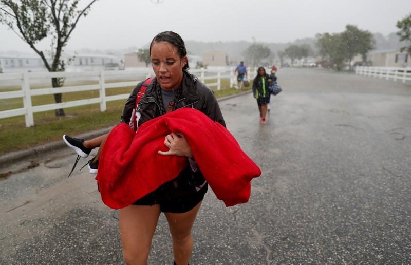 During a driving rain, Maggie Belgie of The Cajun Navy, carries a child evacuating a flooding trailer community during Hurricane Florence in Lumberton, North Carolina, U.S. September 15, 2018. REUTERS