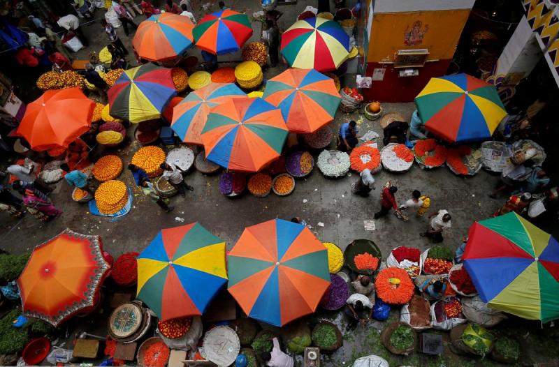 Vendors sit under umbrellas inside a wholesale flower market in Bengaluru, India, April 12, 2018. REUTERS/FILE PHOTO