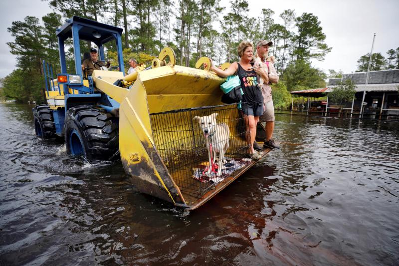 Jimmy Shackleford, 74, of Burgaw transports his son Jim Shackleford and his wife Lisa, and their pets Izzy, Bella and Nala (in the cage) in the bucket of his tractor as the Northeast Cape Fear River breaks its banks during flooding after Hurricane Florence in Burgaw, North Carolina, U.S., September 17, 2018. REUTERS