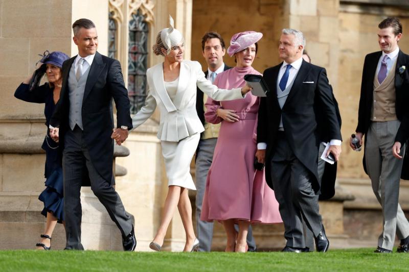 A guest stoops to collect her hat that blew off in the wind as she arrives to attend the wedding of Britain`s Princess Eugenie of York to Jack Brooksbank at St George`s Chapel, Windsor Castle, in Windsor, Britain October 12, 2018. Adrian Dennis/Pool via REUTERS