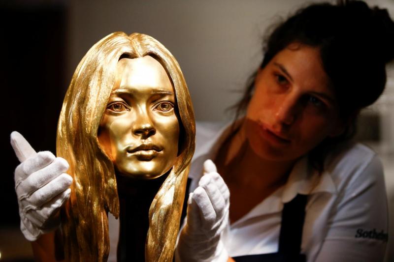 A Sotheby`s employee poses with a bust of Kate Moss in solid 18-carat gold during a photocall for `The Midas Touch` collection at Sotheby`s in London, Britain, October 12, 2018. REUTERS