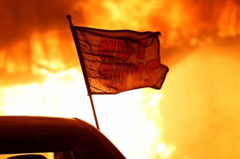 A flag is seen at a burning used car dealership during the Camp Fire in Paradise, California, U.S. November 8, 2018. REUTERS