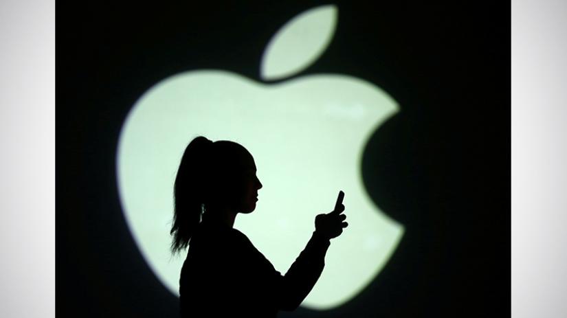 Silhouette of mobile user is seen next to a screen projection of Apple logo in this picture illustration taken on March 28, 2018. REUTERS