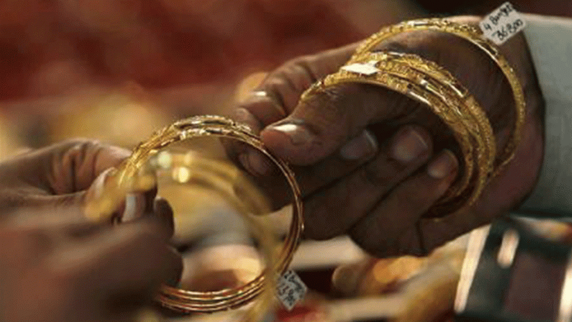 A woman buyer looks at gold bangles at a jewellery shop. REUTERS