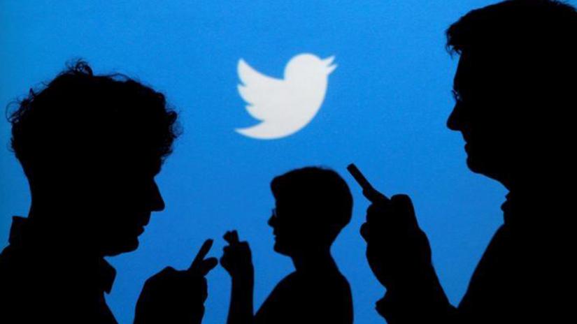 People holding mobile phones are silhouetted against a backdrop projected with the Twitter logo in this illustration picture taken in Warsaw Sep 27, 2013. REUTERS