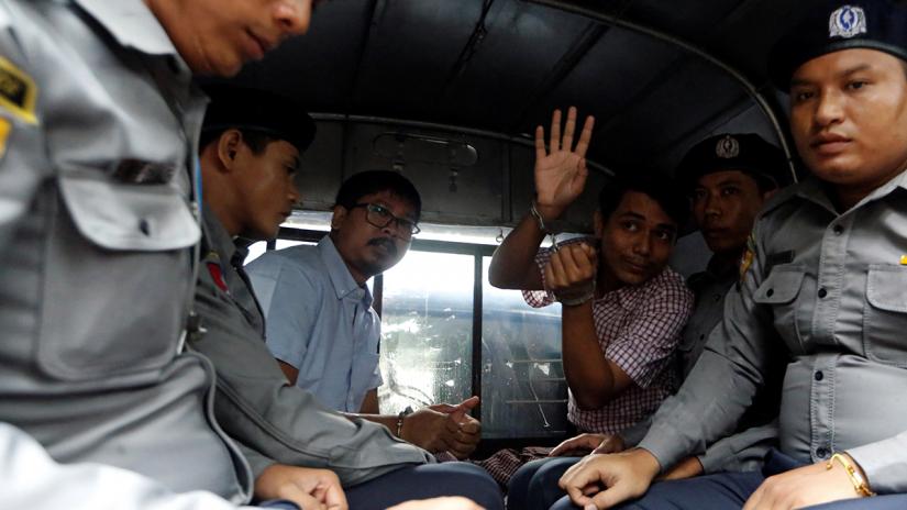 Detained Reuters journalist Wa Lone and Kyaw Soe Oo sit beside police officers as they leave Insein court in Yangon, Myanmar July 9, 2018. REUTERS