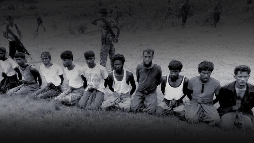This photo was taken on the day the 10 Rohingya men were killed. Paramilitary police officer Aung Min, left, stands guard behind them. The picture was obtained from a Buddhist village elder, and authenticated by witnesses. REUTERS