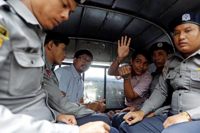Jailed Reuters journalist Wa Lone and Kyaw Soe Oo sit beside police officers as they leave Insein court in Yangon, Myanmar, on July 9, 2018. Reuters