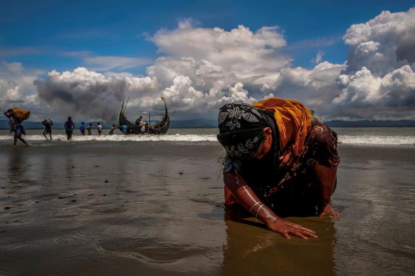 An exhausted Rohingya refugee woman touches the shore after crossing the Bangladesh-Myanmar border by boat through the Bay of Bengal, in Shah Porir Dwip, Bangladesh September 11, 2017. REUTERS/FILE PHOTO