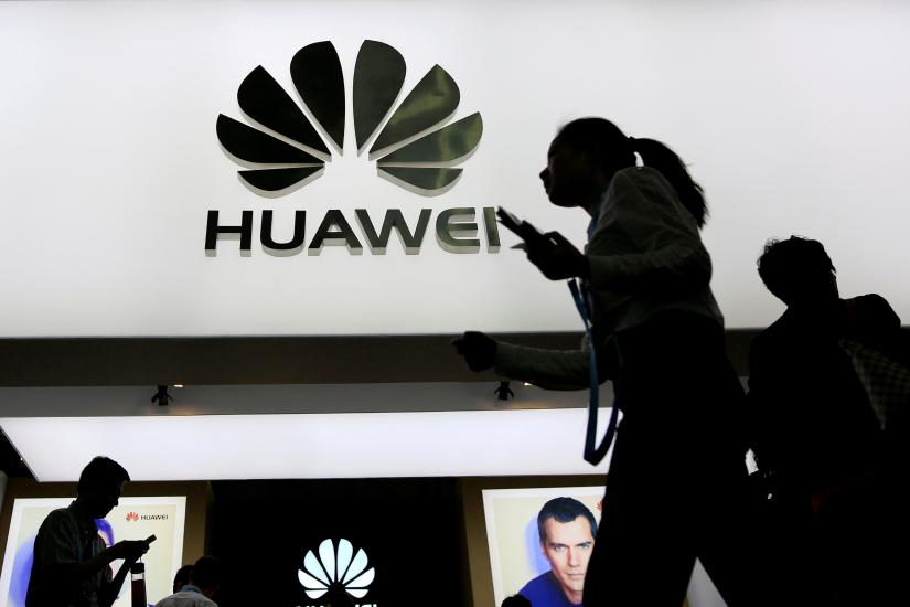 People walk past a sign board of Huawei at CES (Consumer Electronics Show) Asia 2016 in Shanghai, China May 12, 2016. REUTERS FILE PHOTO