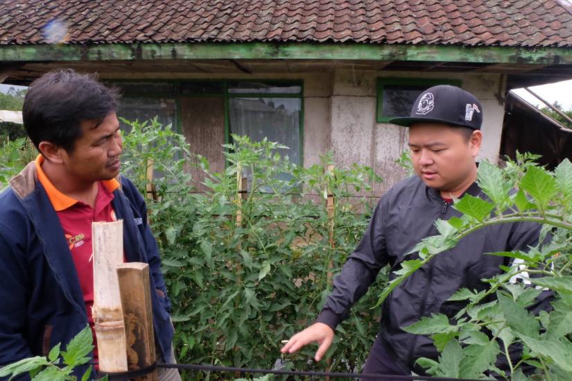 Yohanes Sugihtononugroho (right), co-founder of the CROWDE app, talks to a farmer in Pangalengan, West Java, Indon