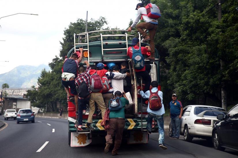 Honduran migrants, part of a caravan trying to reach the U.S., climb on a bus during a new leg of their travel, in Guatemala City, Guatemala October 18, 2018. REUTERS