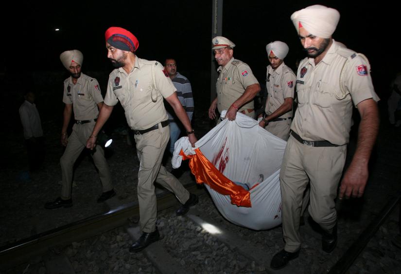 Policemen carry the body of a victim after a train struck a crowd seated on tracks in Amritsar, India, October 19, 2018. REUTERS