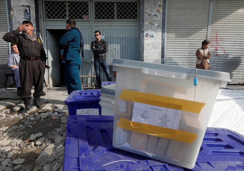 Afghan police officers stand guard while election commission workers prepare ballot boxes and election material at a polling station in Kabul, Oct 19. REUTERS
