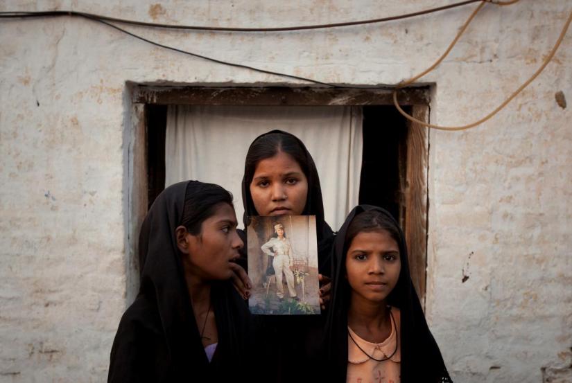 The daughters of Pakistani Christian woman Asia Bibi pose with an image of their mother while standing outside their residence in Sheikhupura located in Pakistan`s Punjab Province November 13, 2010. Standing left to right is Esha, 12, Sidra, 18 and Eshum, 10. REUTERS/FILE PHOTO