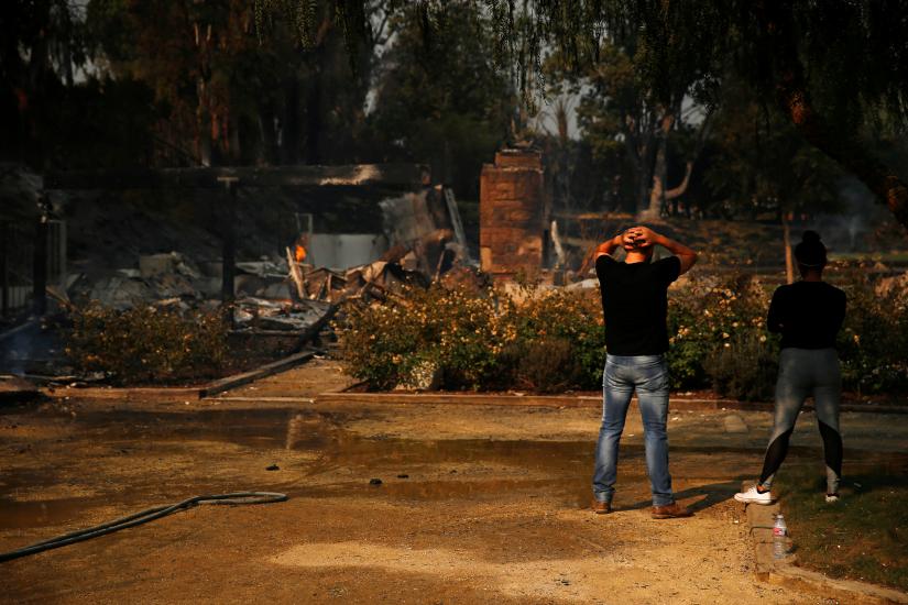 Alexander Tabolsky and Dina Arias look at the destroyed home they lived in as the Woolsey Fire continues to burn in Malibu, California, U.S. November 10, 2018. REUTERS