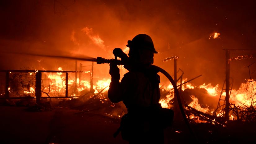 A firefighter hoses down a property engulfed in flames during the Woolsey Fire in Malibu, California, U.S. November 9, 2018. REUTERS