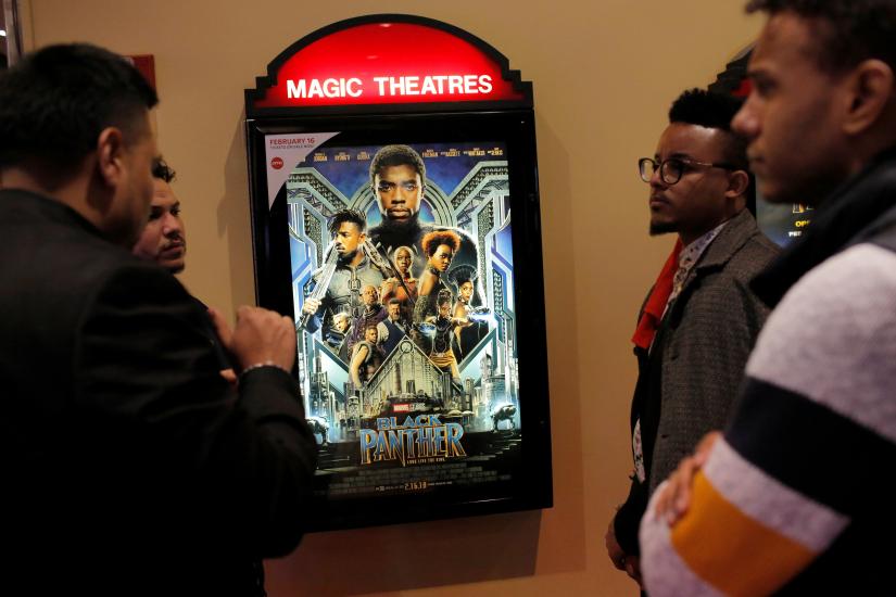 A group of men gather in front of a poster advertising the film `Black Panther` on its opening night of screenings at the AMC Magic Johnson Harlem 9 cinemas in Manhattan, New York, U.S., February 15, 2018. REUTERS