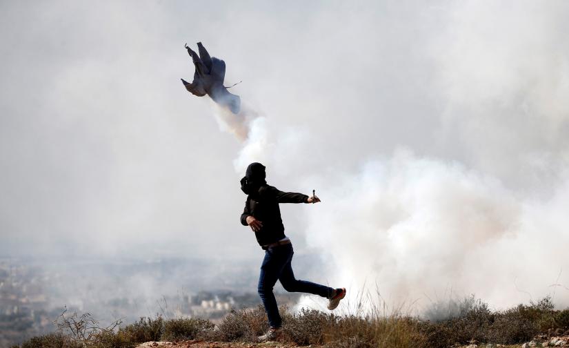 A Palestinian demonstrator hurls back a tear gas canister fired by Israeli troops during a protest against Israeli land seizures for Jewish settlements, in the village of Ras Karkar, near Ramallah in the occupied West Bank Nov 9, 2018. REUTERS