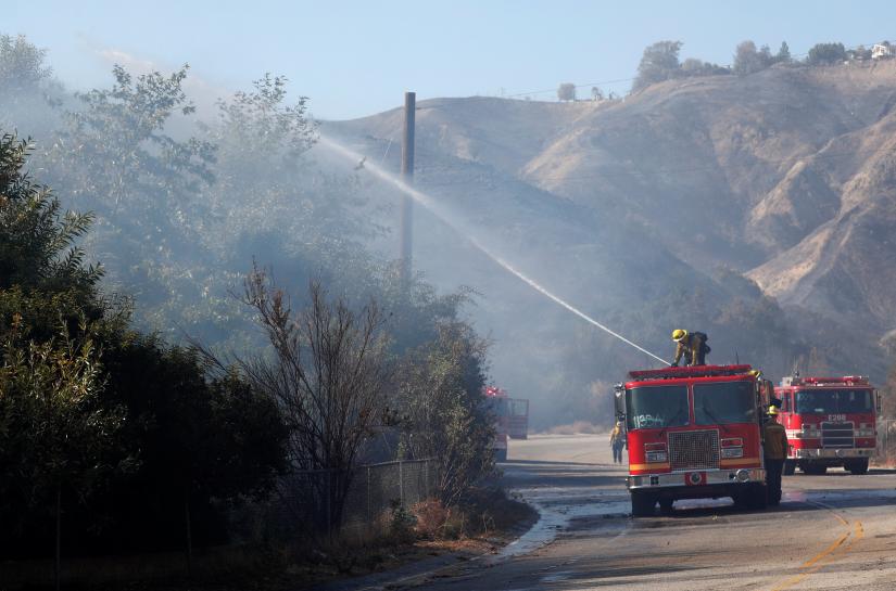 Firefighter sprays water from a fire truck as they battle the Woolsey fire in West Hills, Southern California, U.S. November 11, 2018. REUTERS