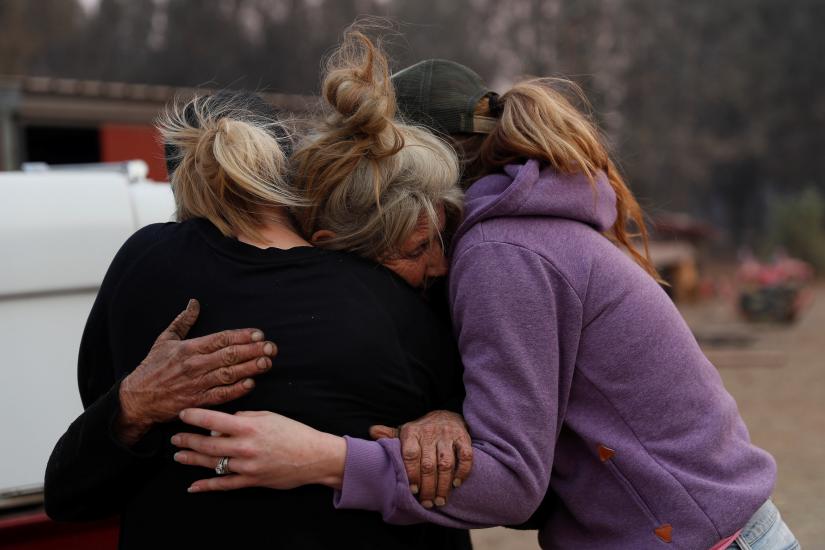 Cathy Fallon (C) who stayed behind to tend to her horses during the Camp Fire, embraces Shawna De Long (L) and April Smith who brought supplies for the horses in Paradise, California, U.S. November 11, 2018. REUTERS