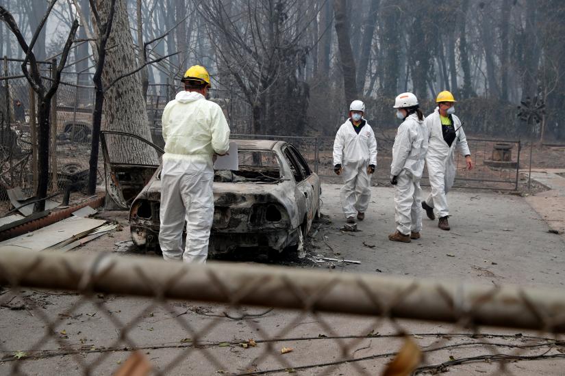 Members of a volunteer search and rescue team from Marin County search for human remains in a car destroyed by the Camp Fire in Paradise, California, US, November 14, 2018. REUTERS