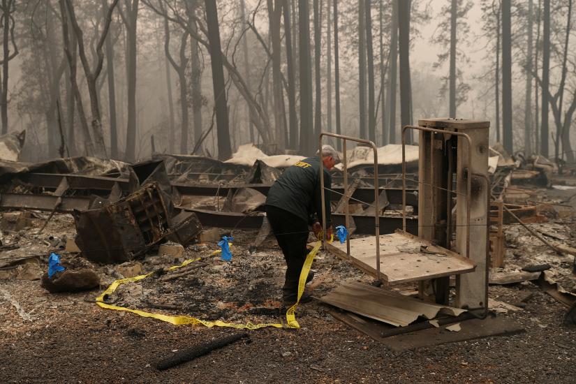 A Butte County Sheriff deputy places yellow tape at the scene where human remains were found during the Camp fire in Paradise, California, US November 10, 2018. REUTERS/File Photo