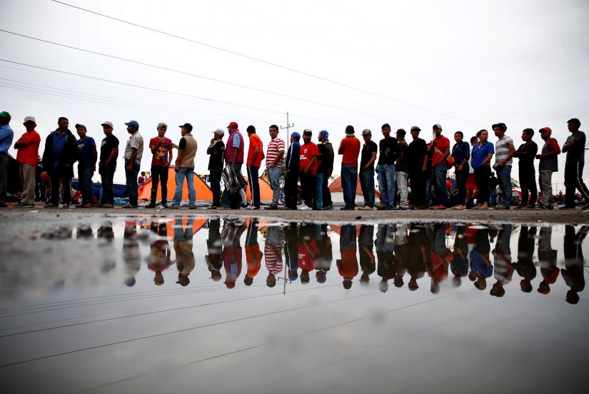Migrants stand in a line to receive cups of coffee in a makeshift camp at a gas station where the migrants wait for buses to the Mexican border city of Tijuana.Nov 16, 2018. REUTERS
