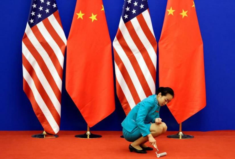 An attendant cleans the carpet next to U.S. and Chinese national flags before a news conference for the 6th round of U.S.-China Strategic and Economic Dialogue at the Great Hall of the People in Beijing, July 10, 2014. REUTERS