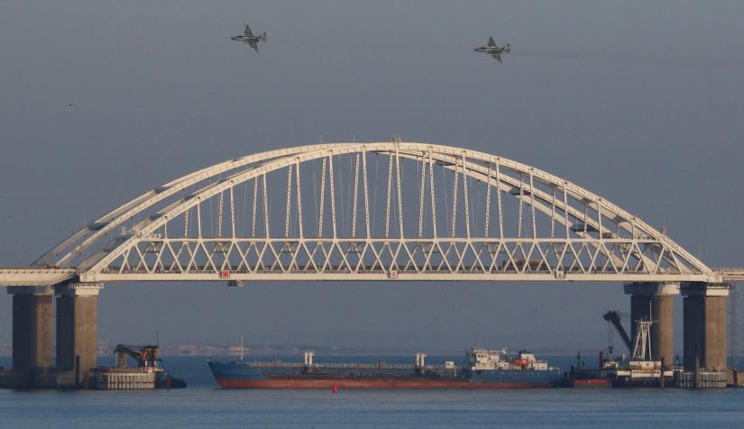 Russian jet fighters fly over a bridge connecting the Russian mainland with the Crimean Peninsula with a cargo ship beneath it after three Ukrainian navy vessels were stopped by Russia from entering the Sea of Azov via the Kerch Strait in the Black Sea, Crimea November 25, 2018. REUTERS