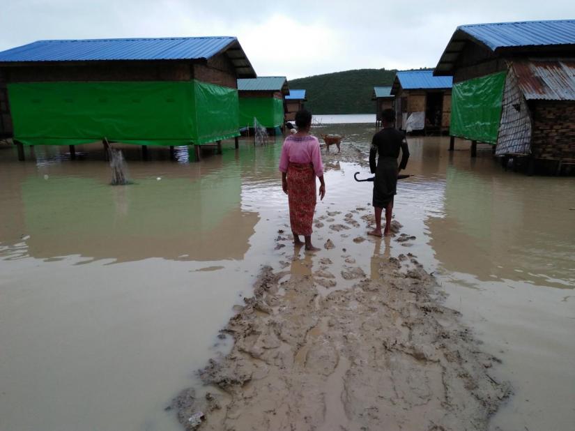 Muslim residents at Taungpaw an internally displaced people`s camp walk through the flood to reach the new house built by the Myanmar government in central Rakhine, Myanmar, June 14, 2018. REUTERS