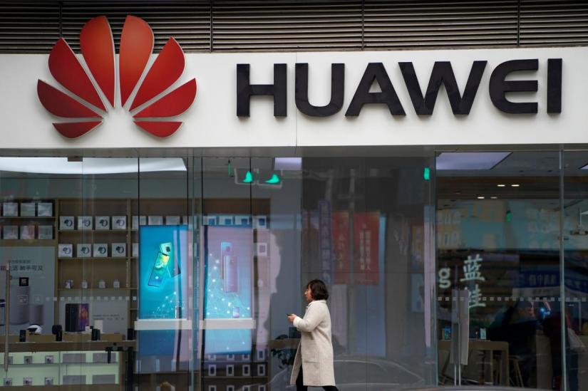 A woman walks by a Huawei logo at a shopping mall in Shanghai, China December 6, 2018. REUTERS