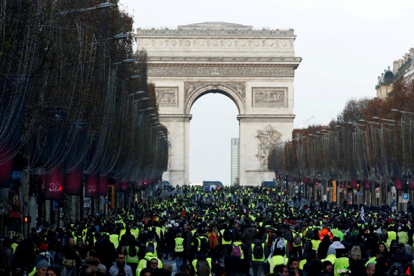 Protesters wearing yellow vests walk on the Champs-Elysees Avenue with the Arc de Triomphe in the background during a national day of protest by the `yellow vests` movement in Paris, France, December 8, 2018. REUTERS