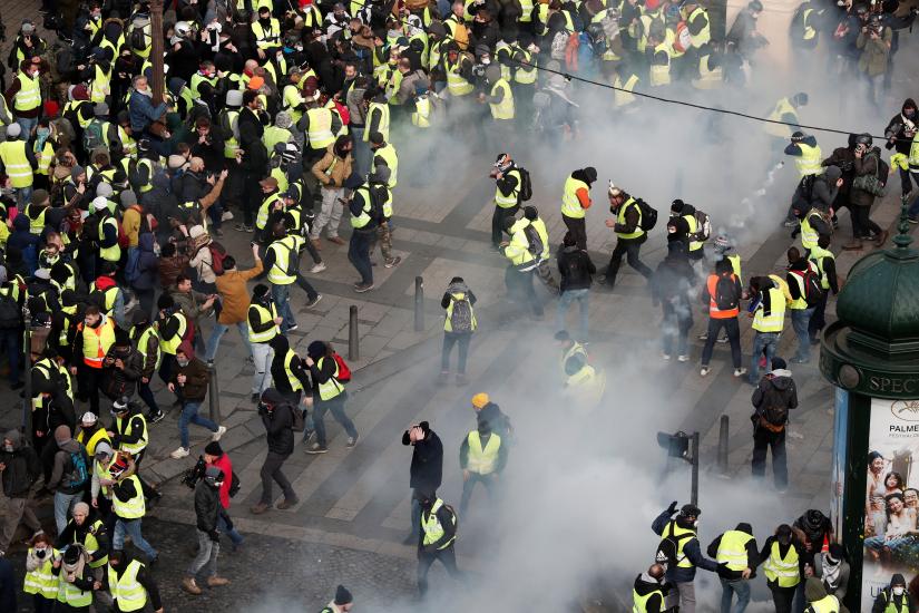 Tear gas floats in the air around protesters wearing yellow vests during clashes with French Gendarmes on the Champs-Elysees Avenue as part of a demonstration by the `yellow vests` movement in Paris, France, December 8, 2018. REUTERS