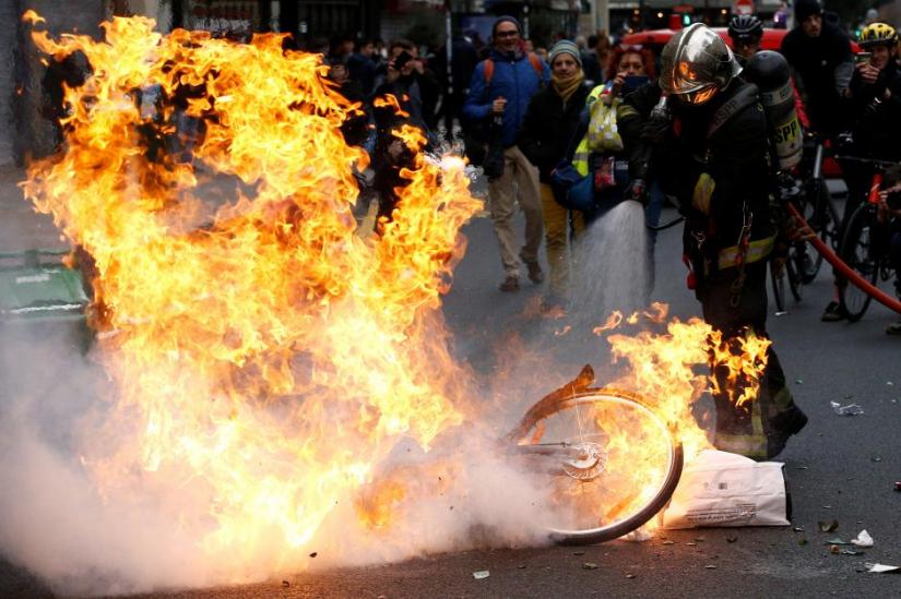 A fireman extinguishes a burning bicycle during clashes with yellow vests protesters as part of a national day of protest by the `yellow vests` movement in Paris, France, December 8, 2018. REUTERS